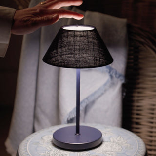 Hand adjusting the light temperature on a dark blue lampshade on a table lamp with a blurred background