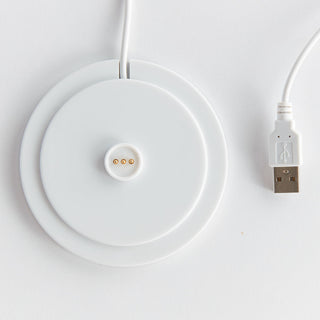 White wireless charging pad with USB cable on a light gray background
